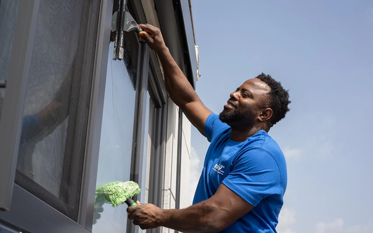 Aktiv Plus Mitarbeiter reinigt Fenster von außen professionelle Glasreinigung