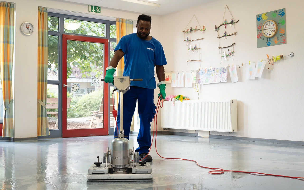 Aktiv Plus Mitarbeiter reinigt Industrieboden mit Reinigungsmaschine professionelle Bodenreinigung