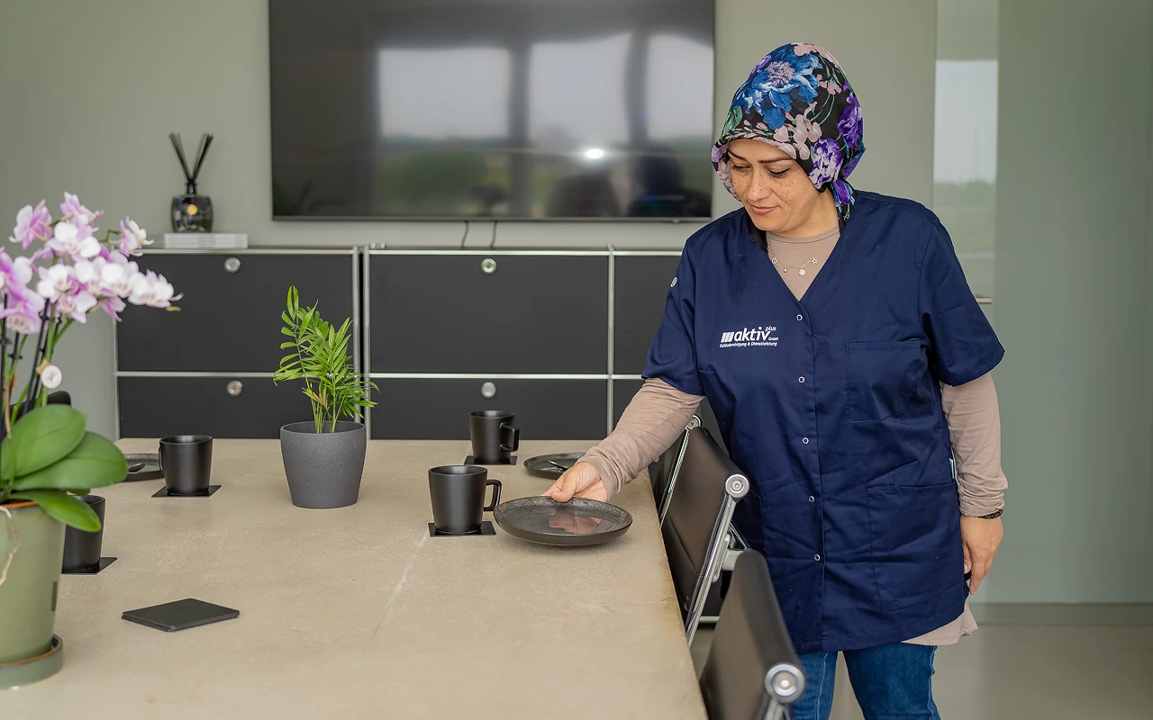 Aktiv Plus Mitarbeiterin bereitet sauberen Besprechungsraum vor professionelle Reinigung